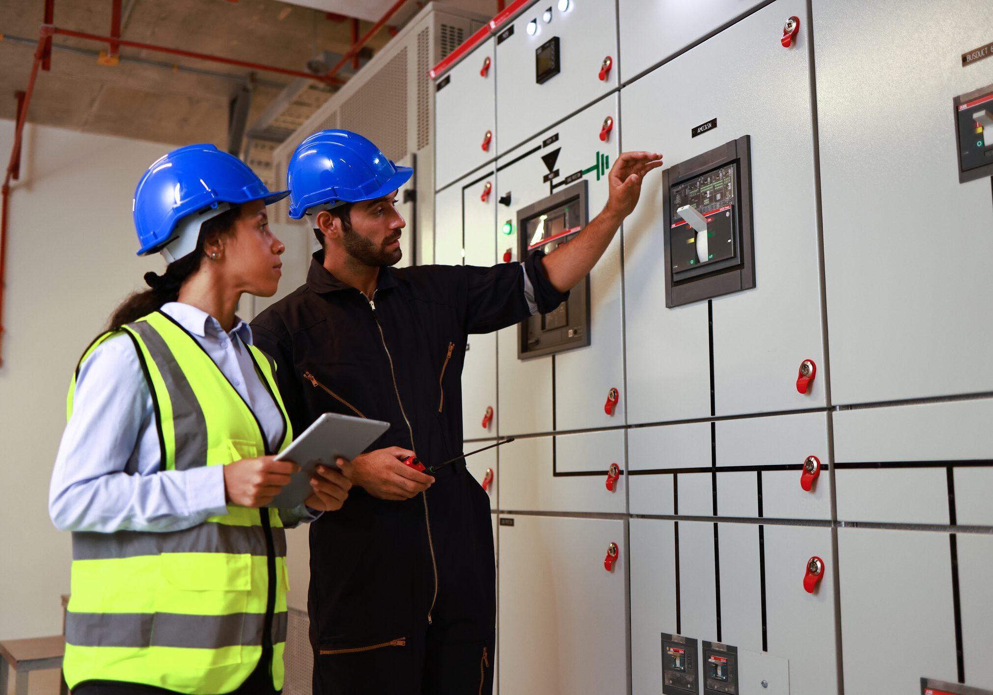 Male and Female colleague electrical engineer work checking at Electrical Distribution Control Room